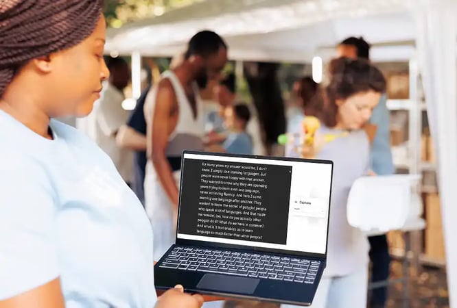 Woman following an institutional event with live captions on a laptop